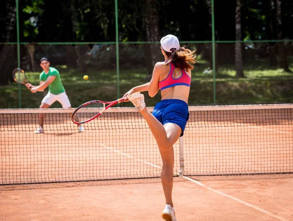 Joven pareja atlética jugando al tenis en la cancha. — Foto de Stock