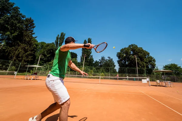 Молодий атлетичний чоловік грає в теніс на корті . — стокове фото