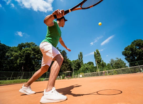 Ung atletisk man spelar tennis på planen. — Stockfoto