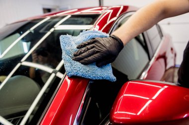 Araba servisi çalışanı mikrofiber bezle araba cilalıyor..