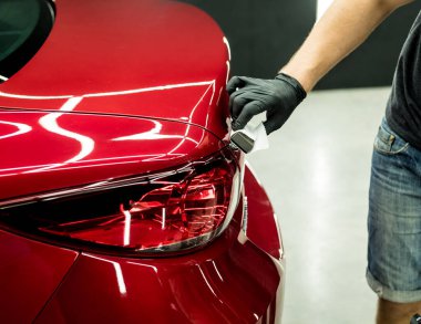 Araba servisi çalışanı bir araba detayına nano kaplama uyguluyor..