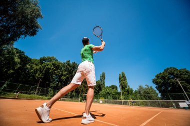 Sahada tenis oynayan genç bir atletik..