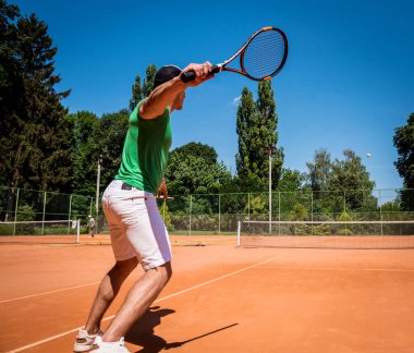 Sahada tenis oynayan genç bir atletik..