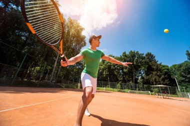 Sahada tenis oynayan genç bir atletik..