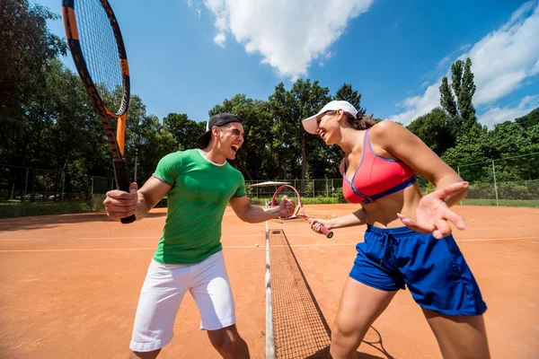 Joven pareja atlética jugando al tenis en la cancha. — Foto de Stock