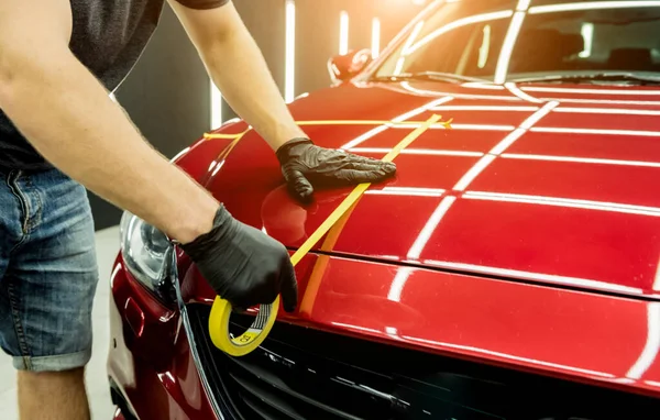 Trabajador de servicio del coche aplicando cinta protectora en los detalles del coche antes de pulir. —  Fotos de Stock