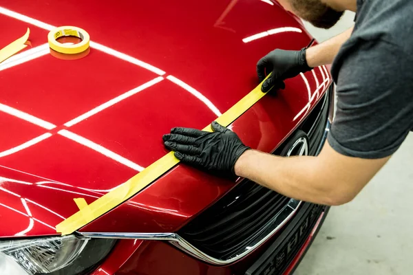 Bil servicearbetare tillämpa skyddstejp på bilen detaljer innan polering. — Stockfoto