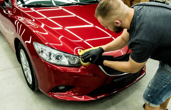 Trabajador de servicio de coches pule los detalles de un coche con pulidor orbital. — Foto de Stock