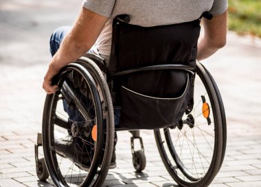 Tekerlekli sandalyedeki engelli adam parkta yürüyor.