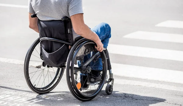 Hombre discapacitado en silla de ruedas preparándose para cruzar la calle en el cruce peatonal —  Fotos de Stock