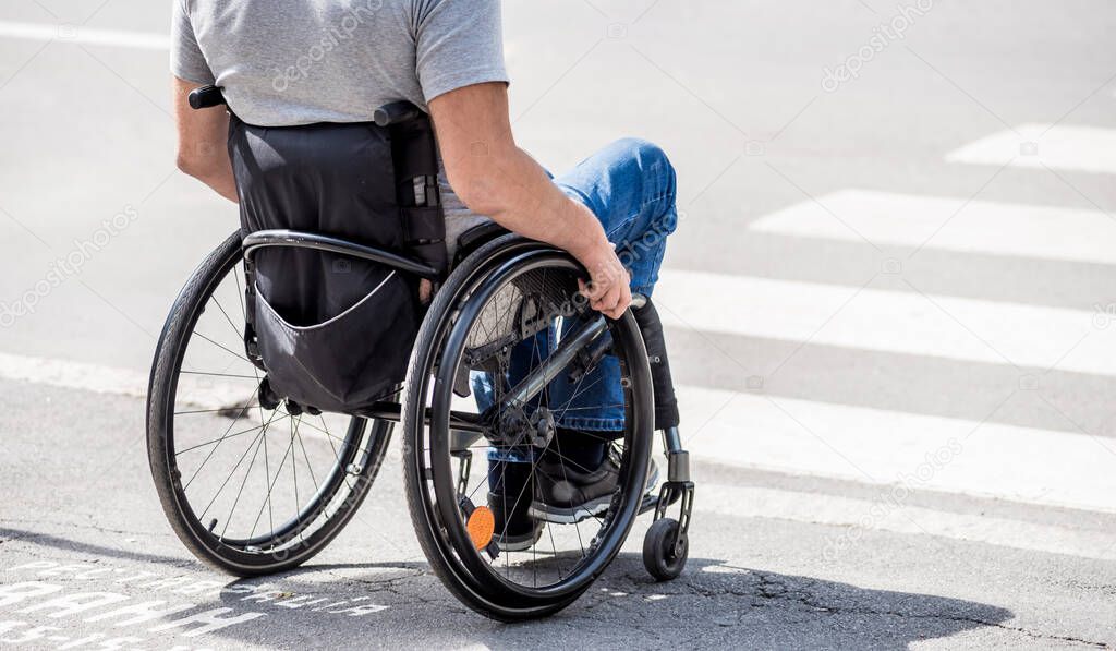 Handicapped man in wheelchair preparing to cross the road on pedestrian crossing