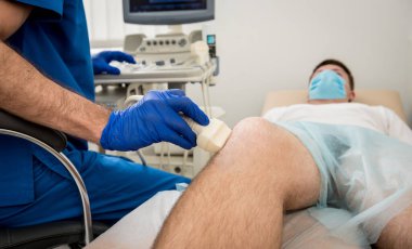 Doktor adamın dizinin ultrasonunu yapıyor..