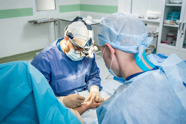 Surgeons in the operating room trying to save the patients hand.