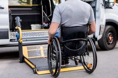 Tekerlekli sandalyedeki bir adam engelliler için araç kaldırıyor.