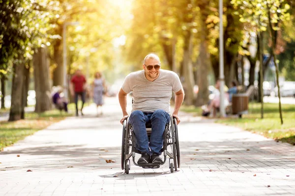 Gehandicapte man in rolstoel loopt in de steeg van het park — Stockfoto