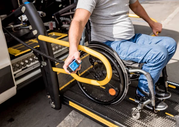 Un uomo sulla sedia a rotelle su un ascensore di un veicolo per disabili — Foto Stock