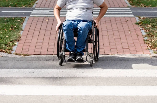 Gehandicapte man in een rolstoel maakt zich op om de weg over te steken op een voetgangersoversteek — Stockfoto