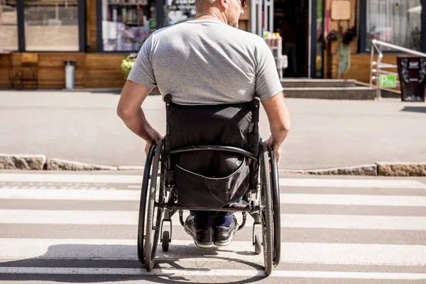 Tekerlekli sandalyedeki engelli adam caddeden karşıya geçiyor. — Stok fotoğraf