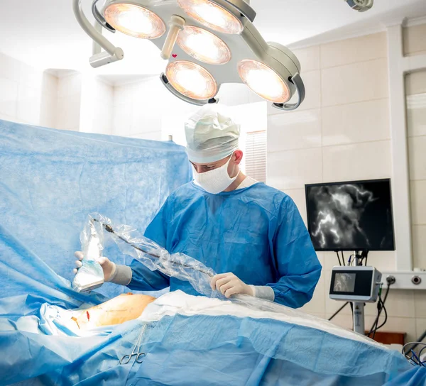 The surgeon uses a portable fluorescence imaging device during breast removal.