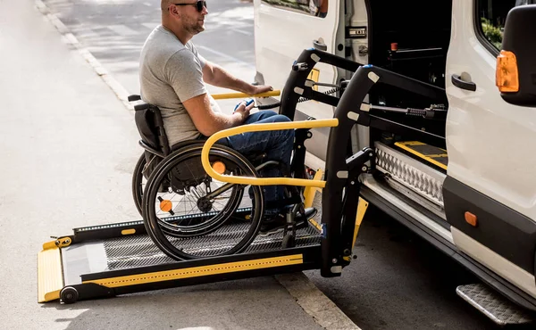 Un uomo sulla sedia a rotelle su un ascensore di un veicolo per disabili — Foto Stock