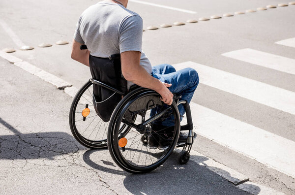 Handicapped man in wheelchair preparing to cross the road on pedestrian crossing