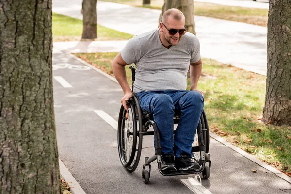 Bezbariérový muž na invalidním vozíku procházka v parku uličky — Stock fotografie