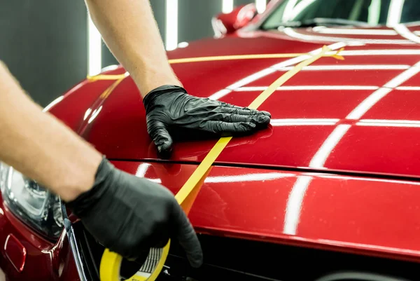 Trabajador de servicio del coche aplicando cinta protectora en los detalles del coche antes de pulir. — Foto de Stock