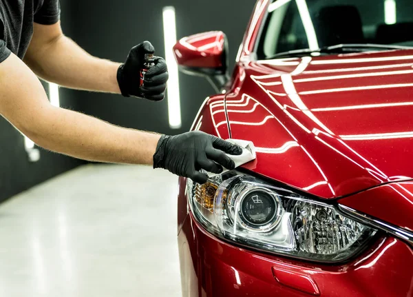 Trabajador de servicio de coches aplicando nano recubrimiento en un detalle del coche. — Foto de Stock