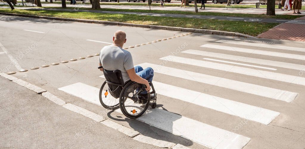 Handicapped man in wheelchair crossing street road