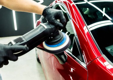 Araba servisi çalışanı, araba detaylarını yörünge cilasıyla parlatıyor..