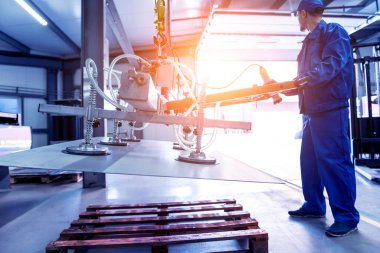 İşçi büyük metal levhalar taşımak için vakum bardakları kullanıyor