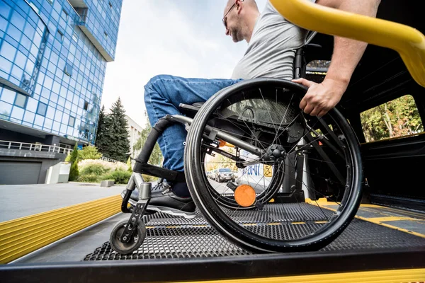 Un uomo sulla sedia a rotelle su un ascensore di un veicolo per disabili — Foto Stock