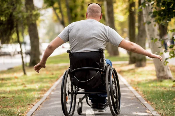 Gehandicapte man in rolstoel loopt in de steeg van het park — Stockfoto