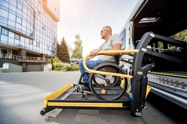 Un uomo sulla sedia a rotelle su un ascensore di un veicolo per disabili — Foto Stock