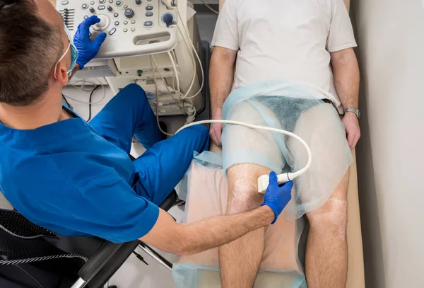 Arzt macht Ultraschall des Kniegelenks des Mannes. — Stockfoto