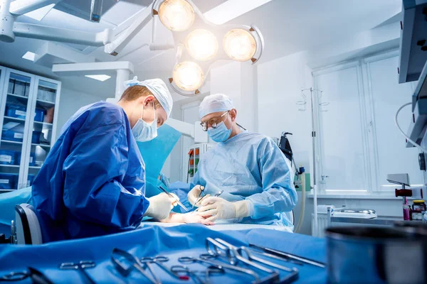 Cirurgiões na sala de cirurgia tentando salvar a mão dos pacientes. — Fotografia de Stock