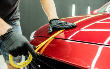 Araba servisi çalışanı cilalamadan önce arabanın detaylarına koruyucu bant takıyor..