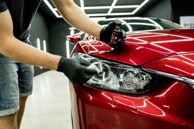 Araba servisi çalışanı bir araba detayına nano kaplama uyguluyor..