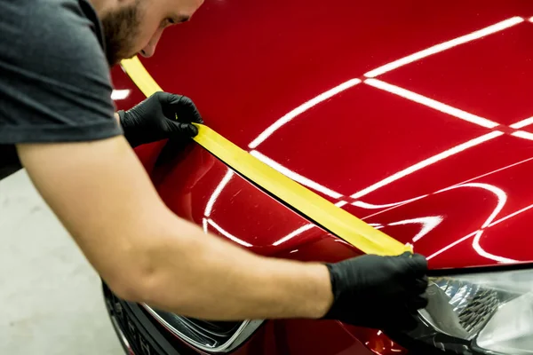 Trabajador de servicio del coche aplicando cinta protectora en los detalles del coche antes de pulir. — Foto de Stock