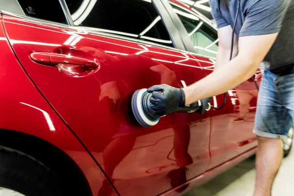 Autoservice-Mitarbeiter poliert ein Auto mit Orbitalpolierer. — Stockfoto