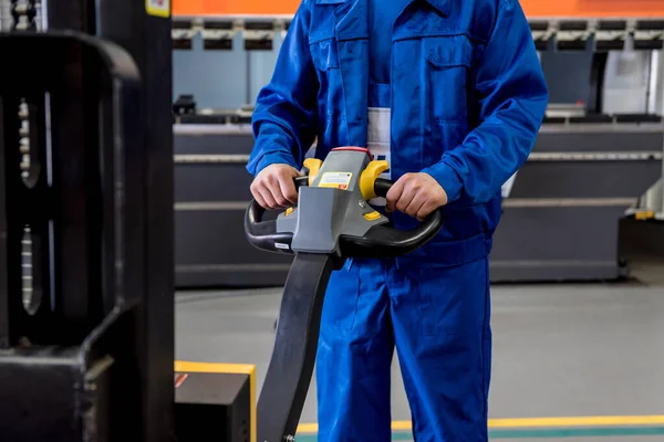 Seorang pekerja di sebuah gudang menggunakan stalet tangan untuk mengangkut palet. — Stok Foto