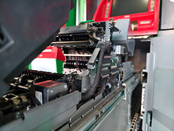 Worker in uniform repairing internal components of automated teller machine