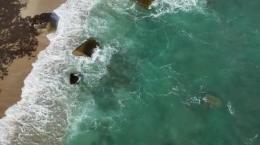 Dev okyanus dalgaları, büyük kaya taşlarıyla boş kumsallara çarpıp köpürüyor.. 