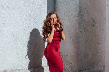 Güzel genç kadın yanındaki duvar eski bir tren konumu olan bir uzun kırmızı gece elbisesi