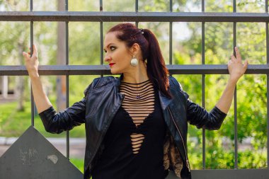 Eski bir metal çit yanında bir deri ceket durduğunu kadında