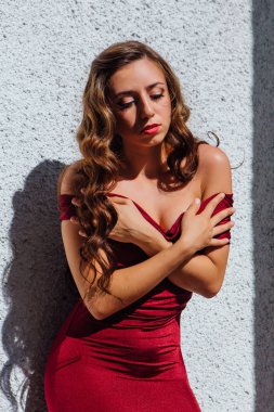 Uzun kırmızı gece elbisesi ayakta duvar eski yanında güzel genç kadın