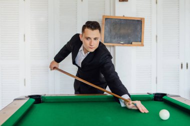 Bilardo oyunu tek başına oynarken klasik kılık giyinmiş genç yakışıklı adam