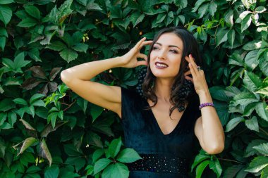 Siyah üzüm bir küpe gibi tutarak siyah elbiseli Genç Seksi esmer portresi.