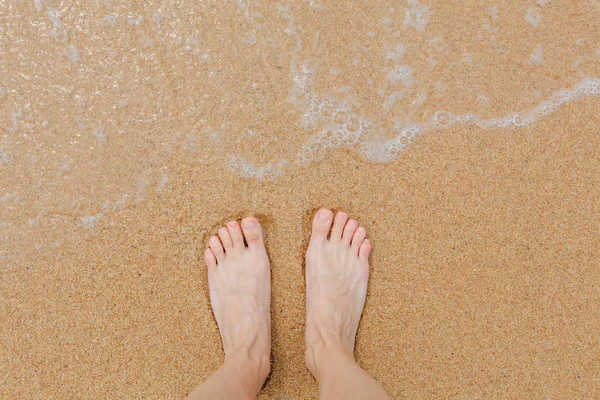 海に洗われて海岸に裸の女性の足 — ストック写真