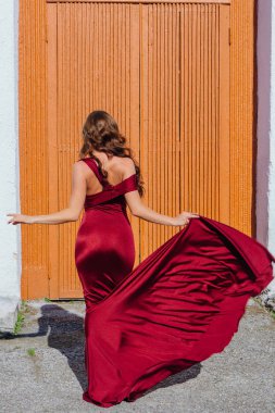 Arkadan görünüş eski kapı yanındaki bir tren konumu olan bir uzun kırmızı gece elbisesi içinde güzel bir genç kadın